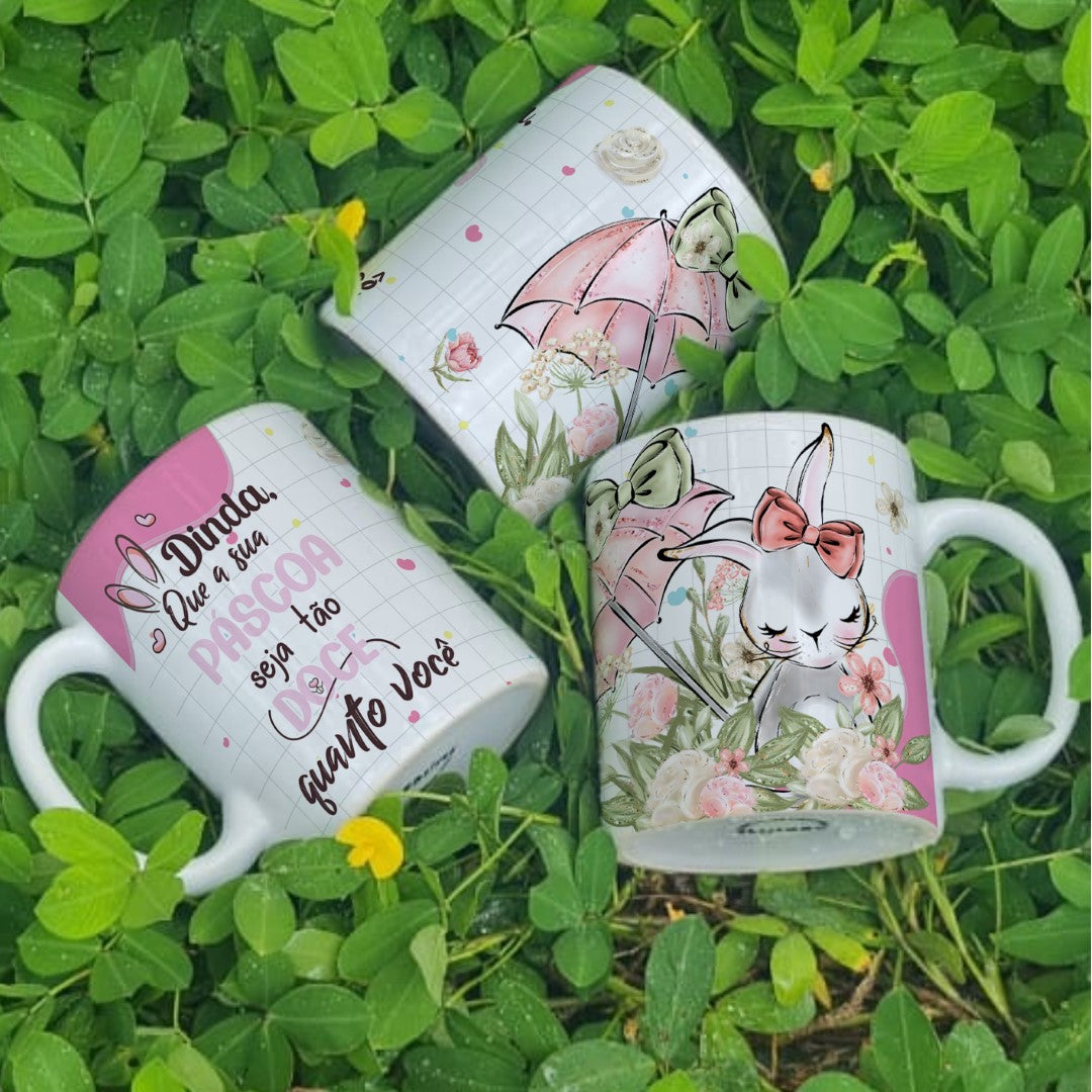 Three decorative mugs with floral and rabbit designs on a grass background