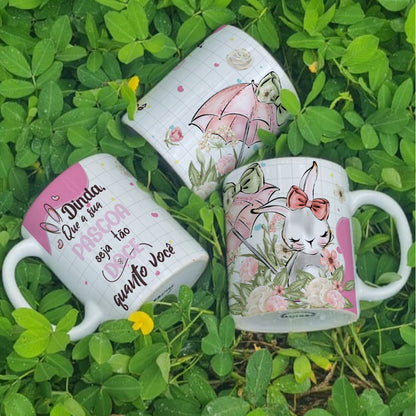 Three decorative mugs with floral and rabbit designs on a grass background