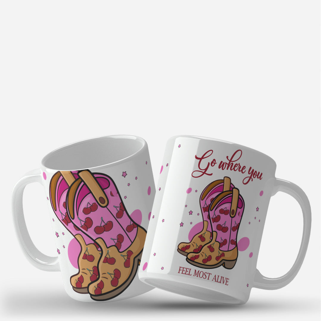 "Go Where You Feel Most Alive" mug wrap design featuring pink cowboy boots with red cherries, set against a background of pink stars and dots, with an inspirational quote in red text.