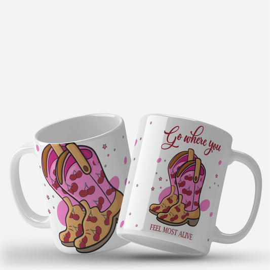 "Go Where You Feel Most Alive" mug wrap design featuring pink cowboy boots with red cherries, set against a background of pink stars and dots, with an inspirational quote in red text.